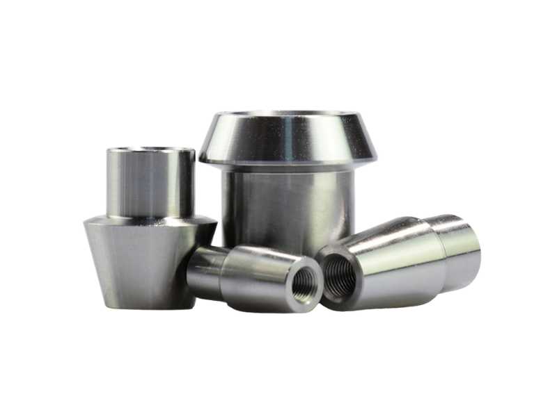 Assorted metal bushings and spacers with threaded interiors, arranged on a white background.