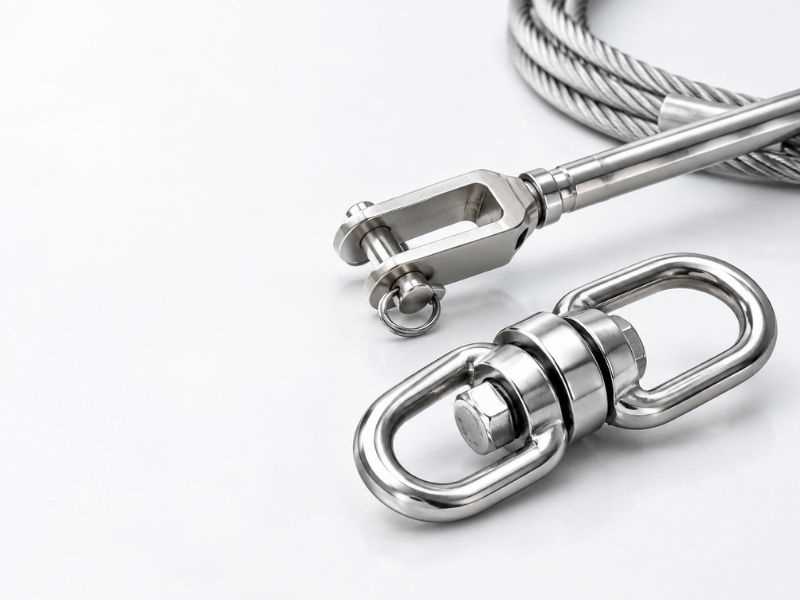 Stainless steel rigging swivel next to a turnbuckle and wire rope assembly