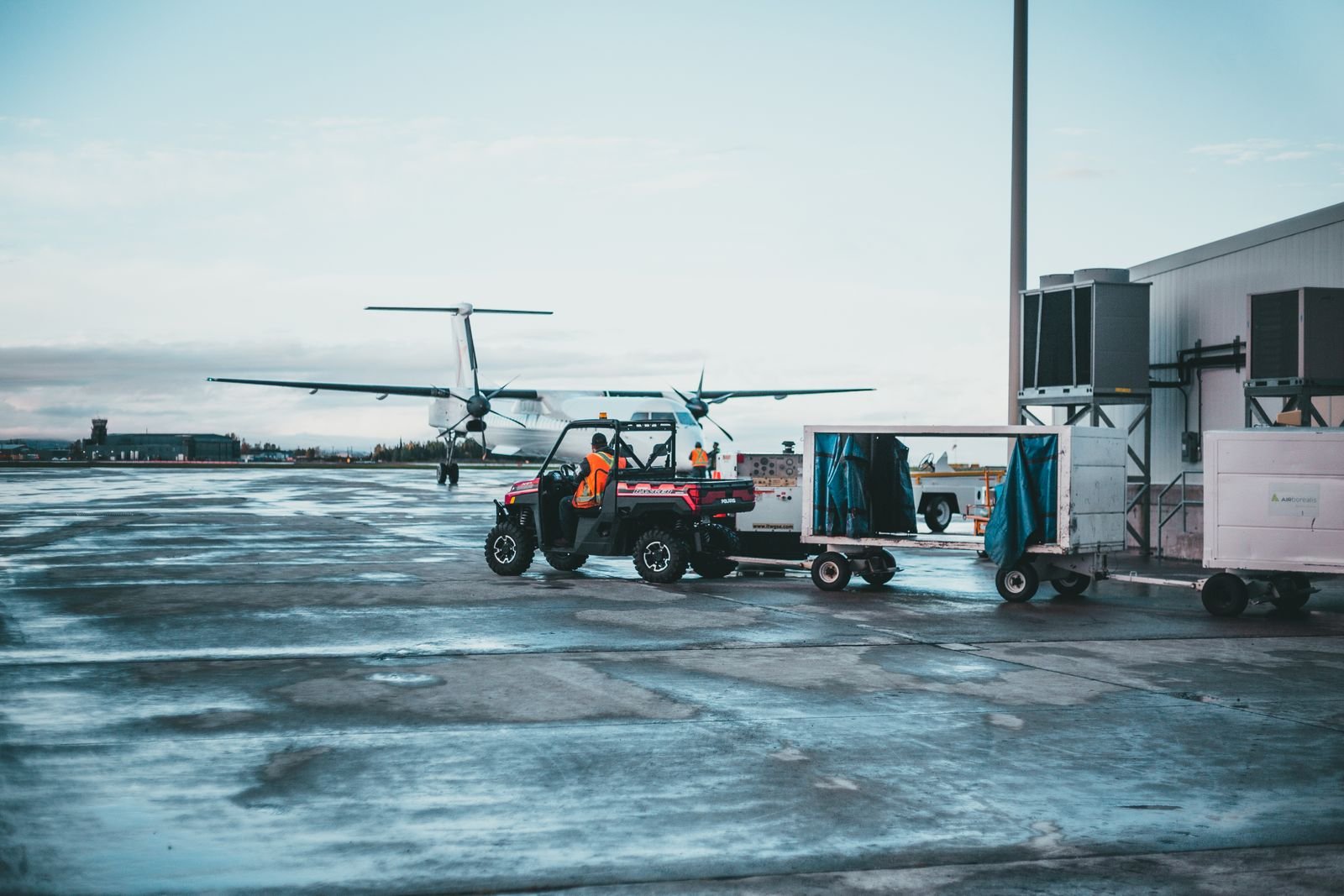 Airport ramp with a ground vehicle towing a baggage cart