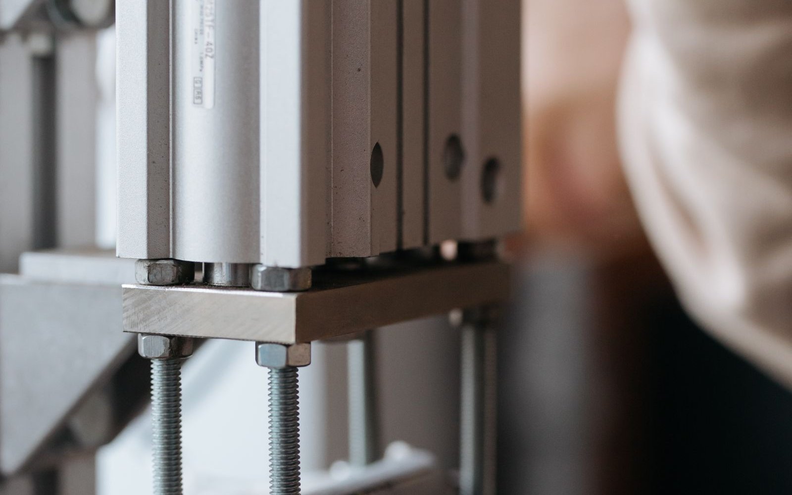 Pneumatic cylinder mounted on a plate with threaded studs