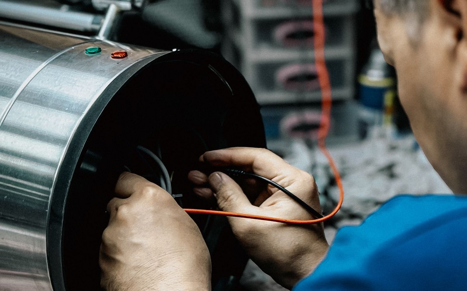 Technician testing a cylindrical unit on a workshop bench