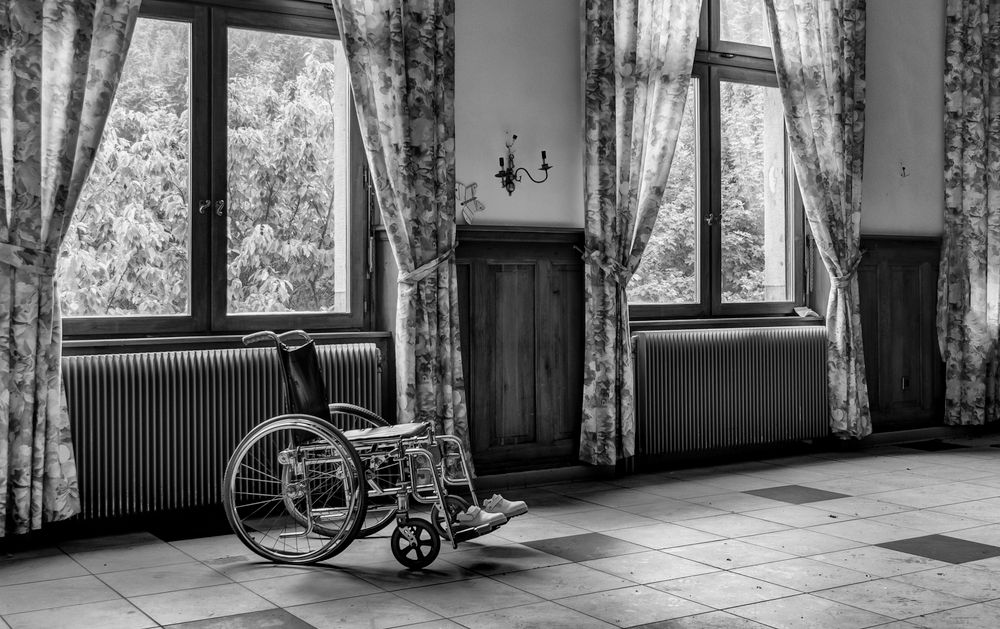 Empty wheelchair standing by a window