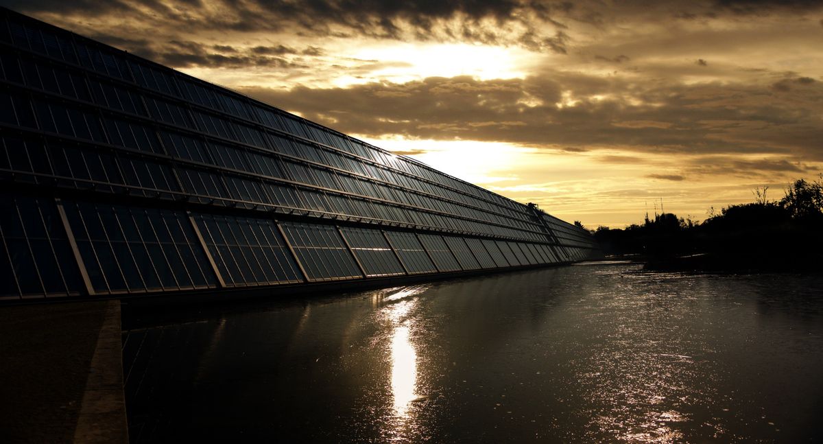 Solar array beside calm water at sunset